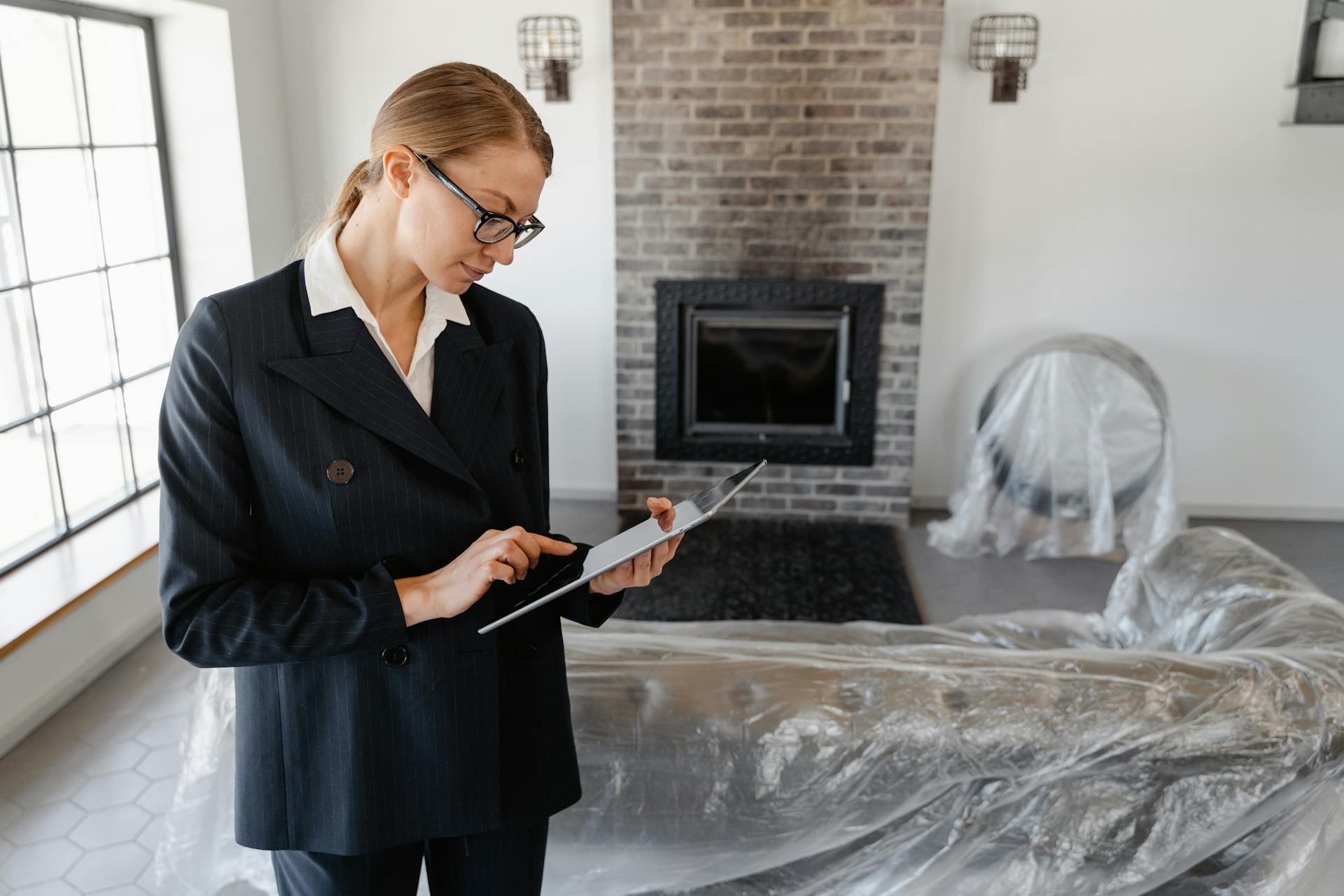 A real estate agent in a suit uses a digital tablet to review documents in a modern living room.