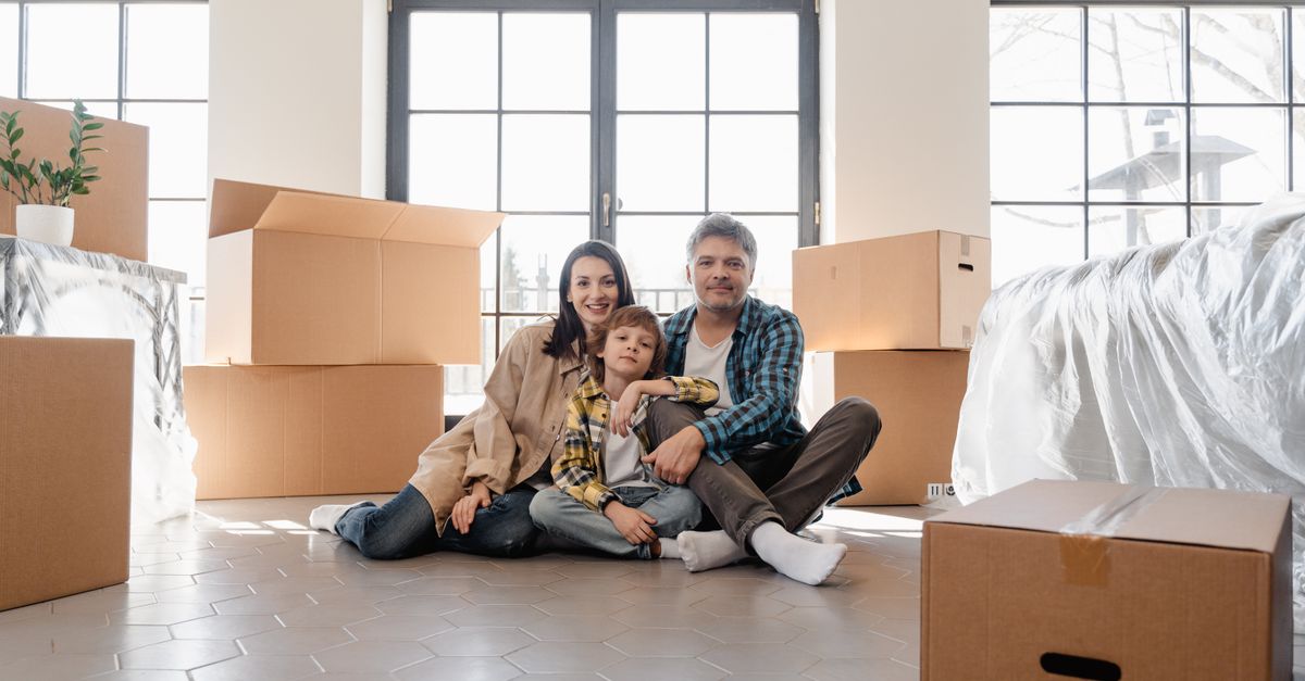 A joyful family sitting together amidst moving boxes, marking a new beginning in their home.