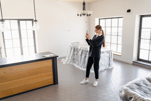 A real estate agent taking pictures of a modern, empty house interior.