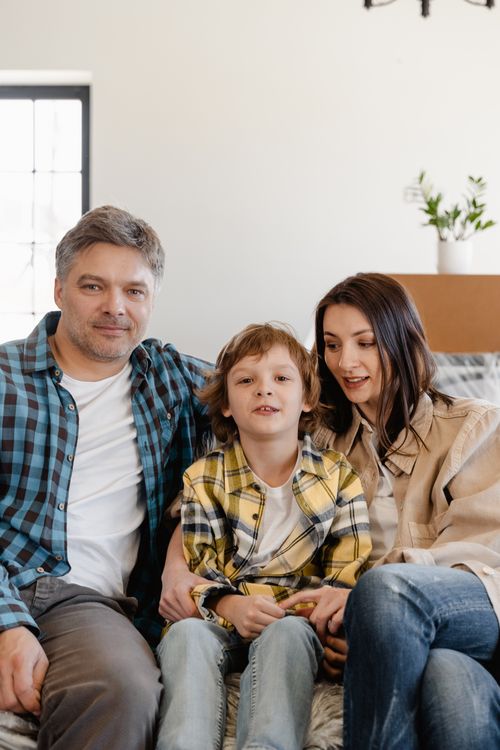 Free An adult couple and their child enjoying quality time at home on the couch. Stock Photo