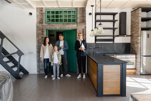 Free A family with a realtor viewing a modern industrial-style kitchen in a new home. Stock Photo
