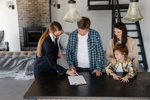 Free Happy family signing a real estate contract with agent inside their new home. Stock Photo