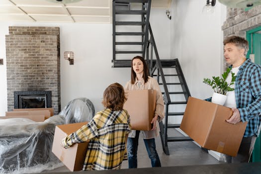 A family carrying boxes and a plant while moving into a new home with an industrial-style interior.