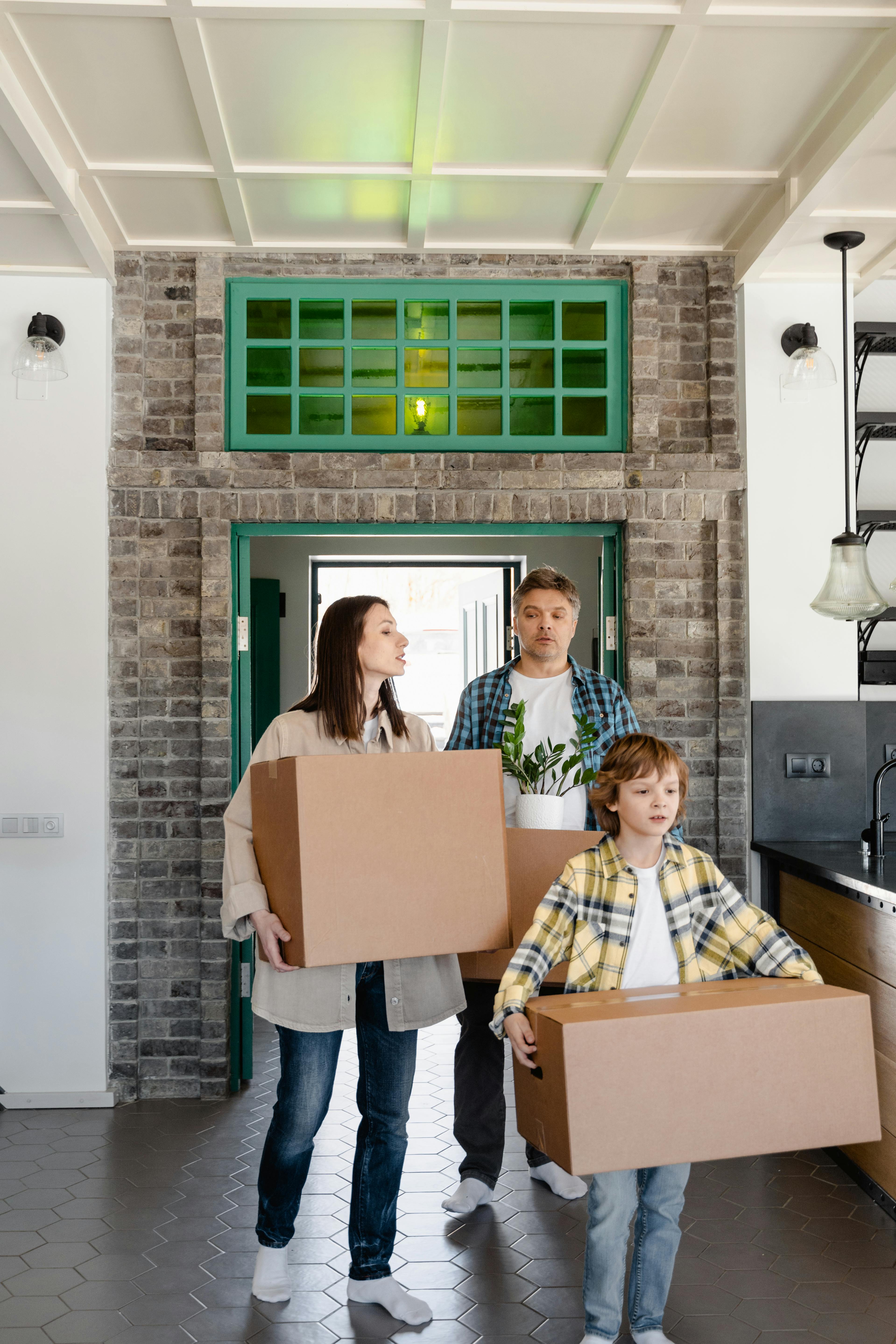 a family walking inside the house while carrying boxes