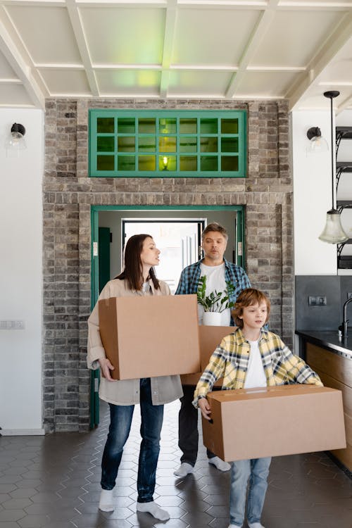 Free A Family Walking Inside the House while Carrying Boxes Stock Photo