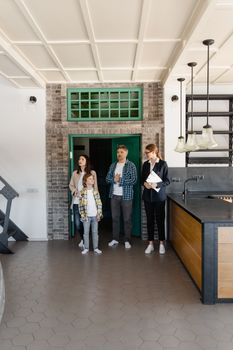 A family touring a modern home interior with a real estate agent, considering a purchase.