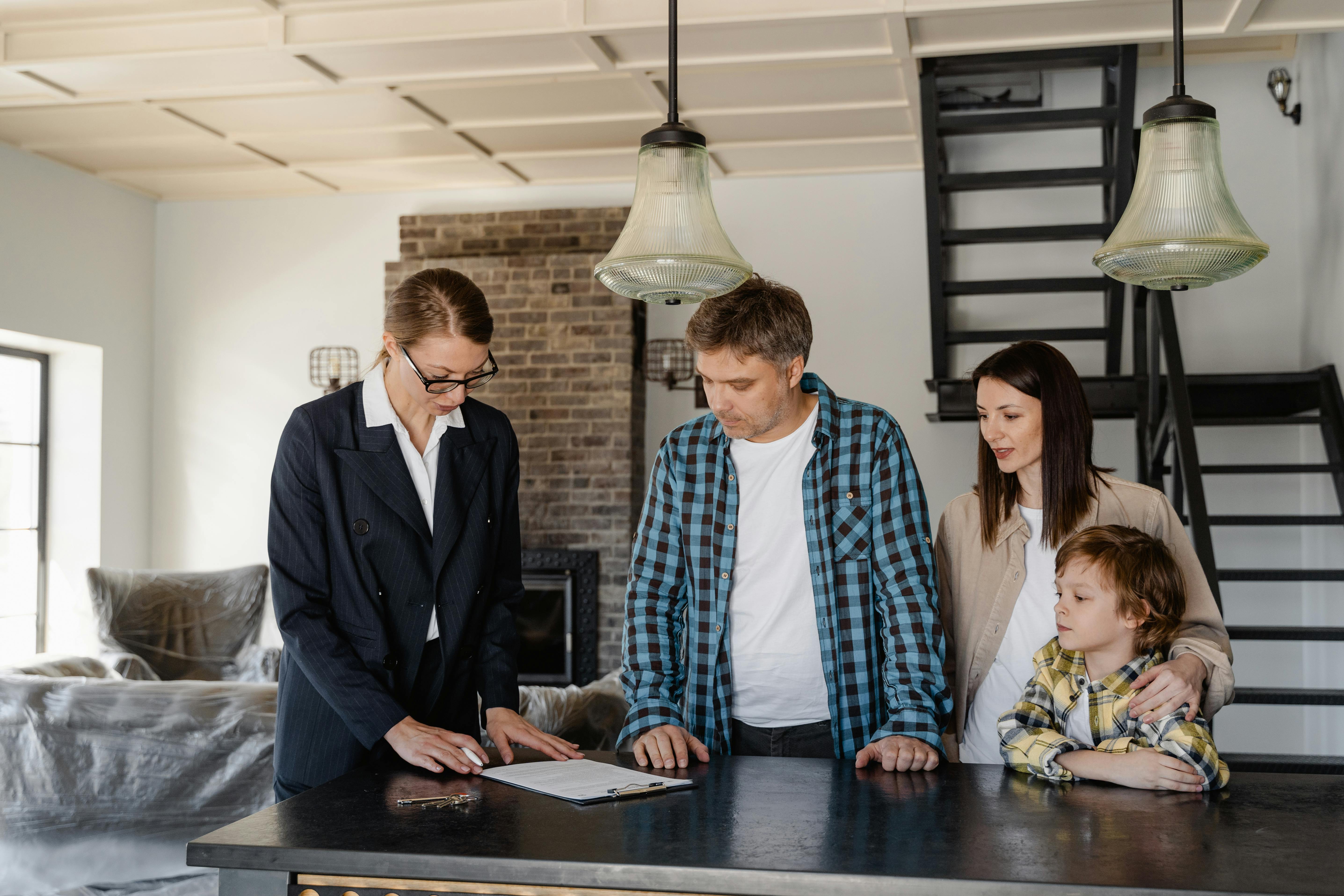 Family signing documents with a real estate agent in their new home interior.