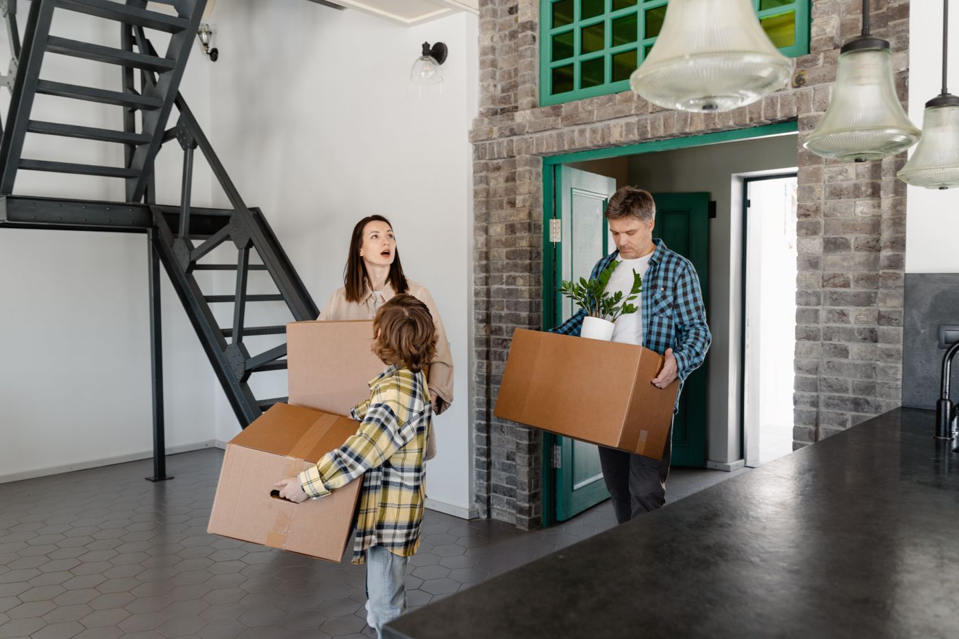 New homeowners carrying a moving box toward a house