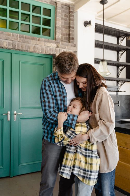 Free A joyful family shares a group hug in their stylish kitchen, showcasing love and unity. Stock Photo