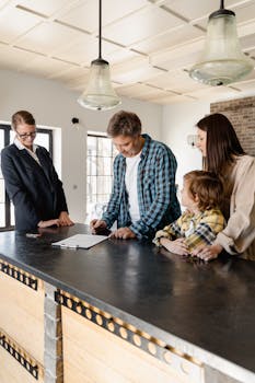 Family with a child signing a real estate agreement in a bright, modern kitchen with a realtor.