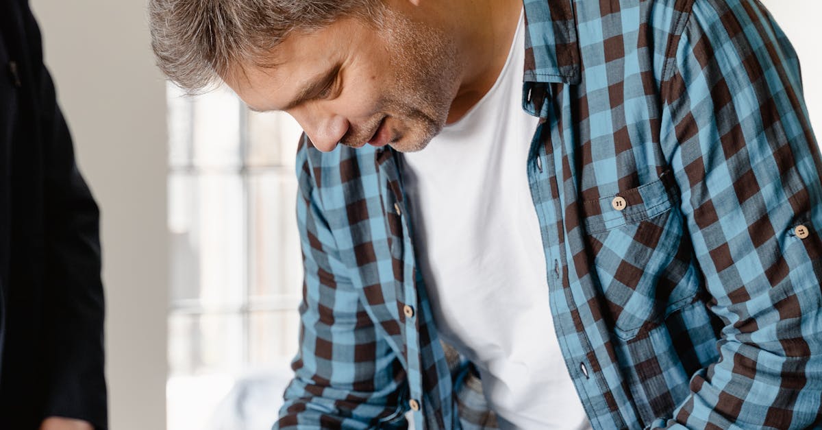 Man in Blue and White Plaid Dress Shirt Writing on White Paper