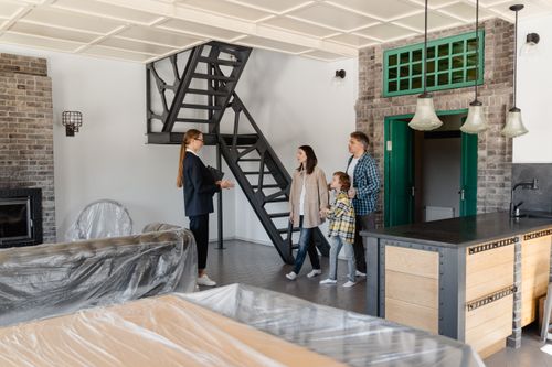 Free Family explores a newly purchased home with their real estate agent guiding them indoors. Stock Photo