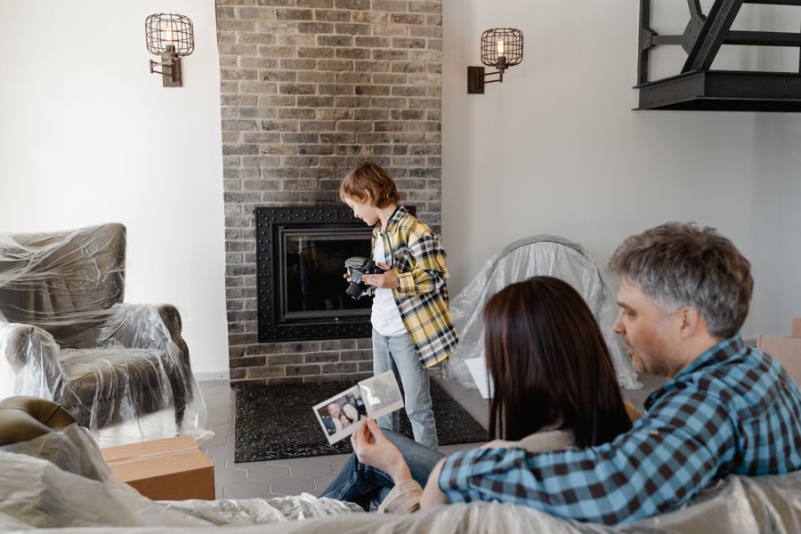 Family reminiscing over photos while moving into a new home with fireplace.