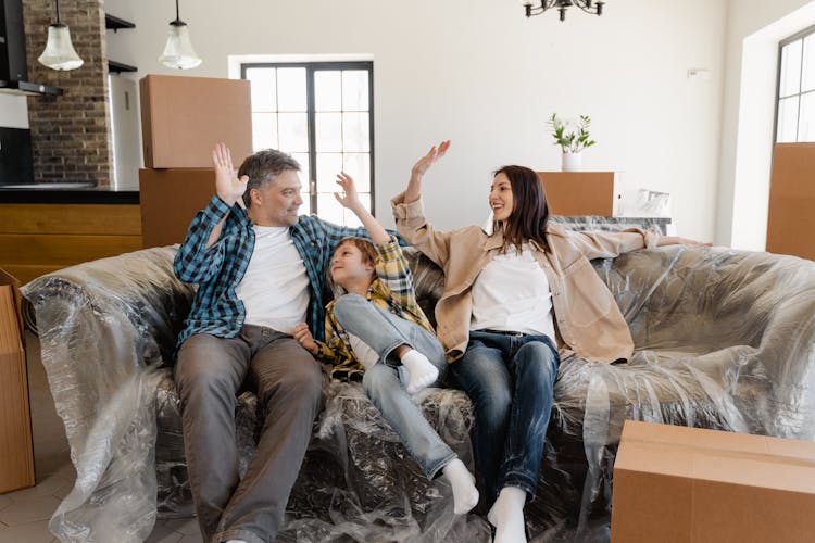 Happy Family Sitting On The Couch Covered With Plastic 