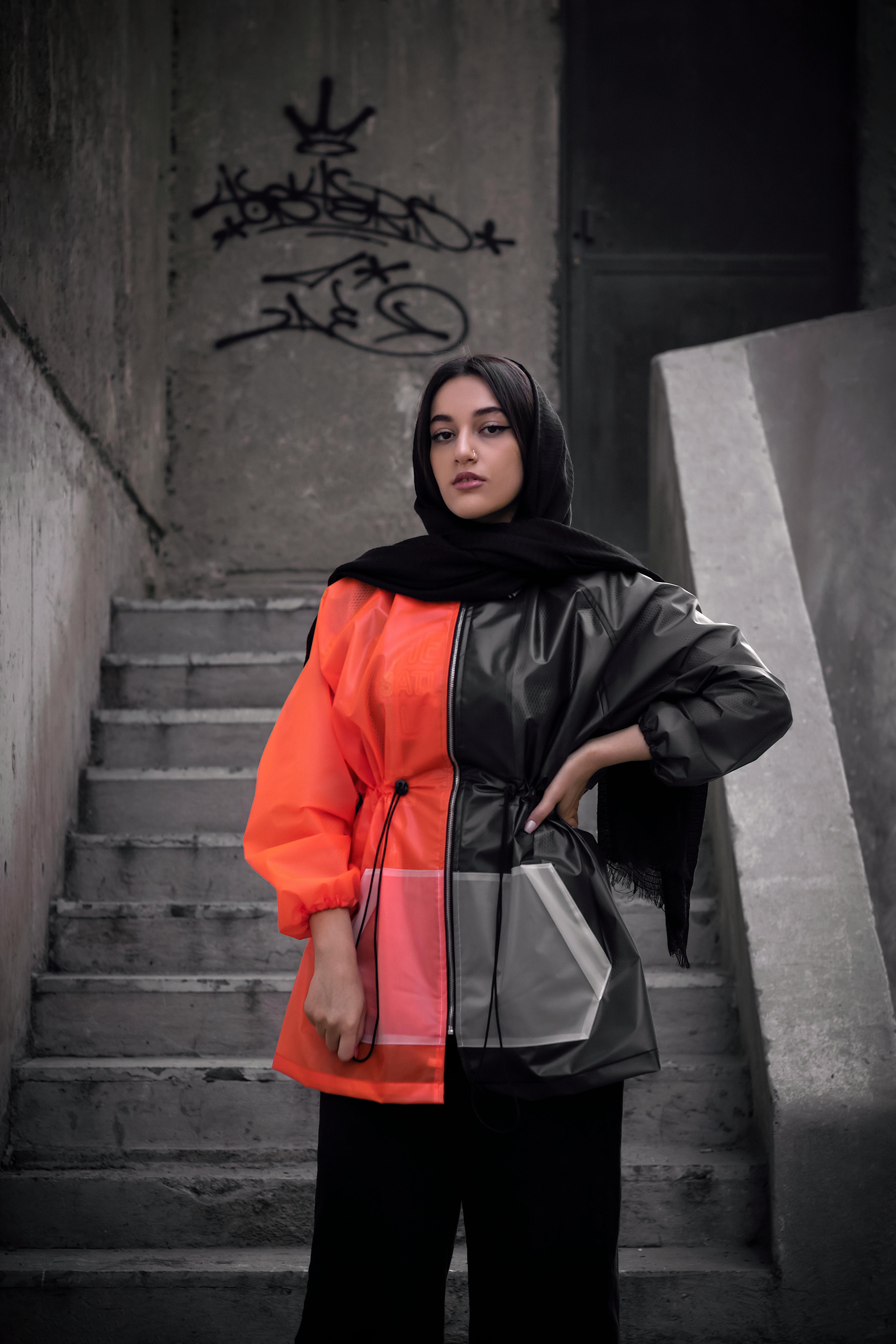 Woman in hijab and stylish coat poses on concrete stairs. Urban fashion.
