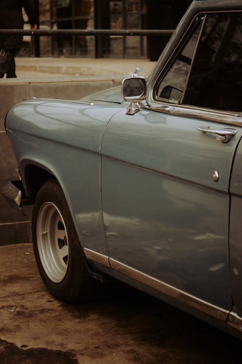Free Detail of blue old timer automobile parked on street near concrete border and black metal railing in city near building Stock Photo