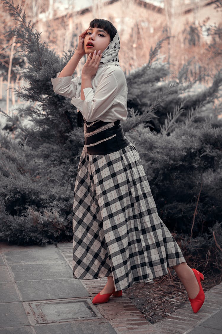 
A Woman Wearing A Plaid Skirt And A Headscarf