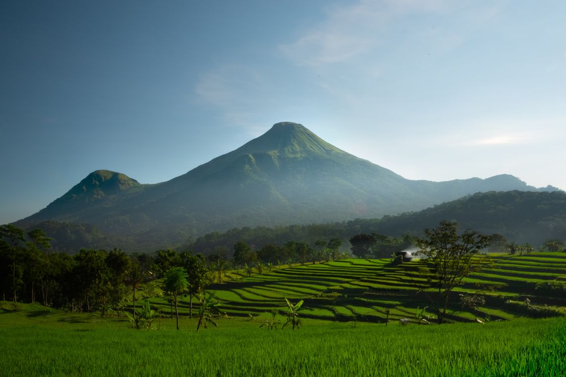 A Green Grass Field Near the Mountain Under the Blue Sky and White ...