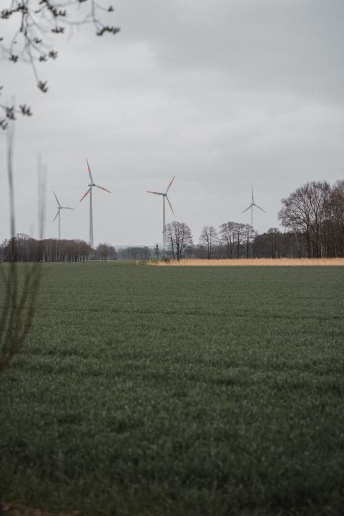 Free Scenic view of wind turbines against a green grass field and cloudy sky in Germany. Stock Photo