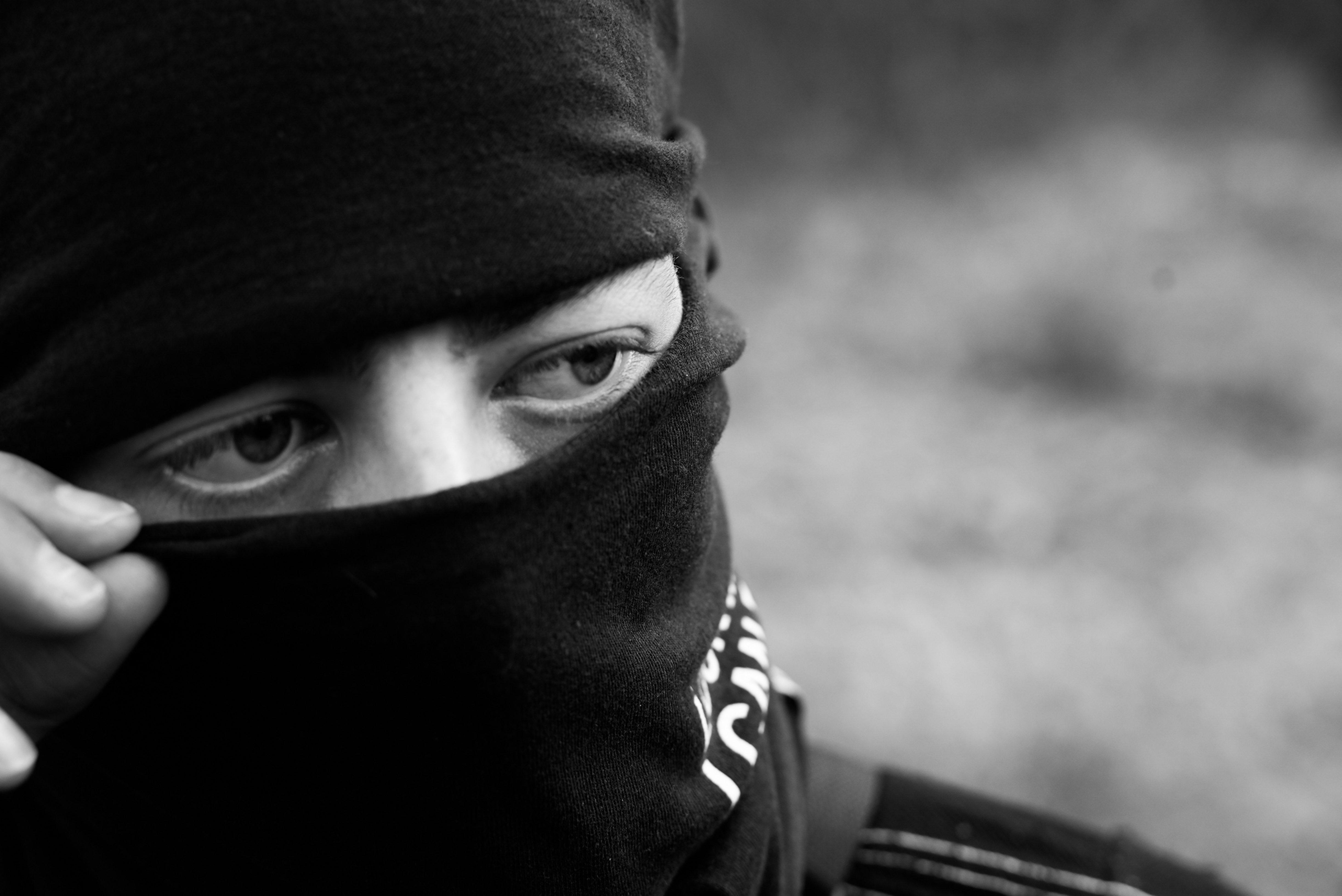 Black and white close-up of a person wearing a balaclava, focus on eyes.
