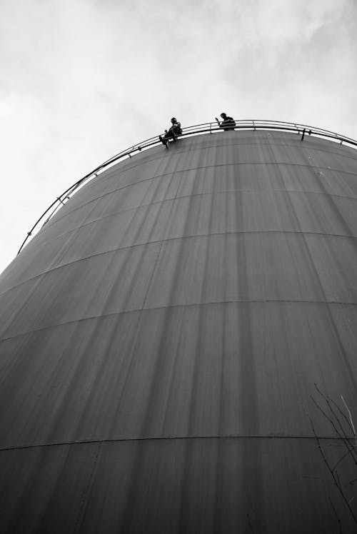 Free Men Standing on Top of a Storage Tank Stock Photo