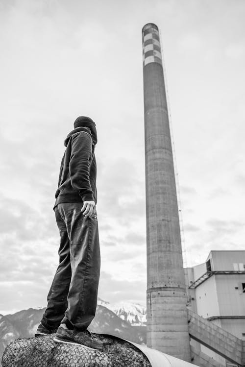 Grayscale Photo of a Person Standing Near a Tower