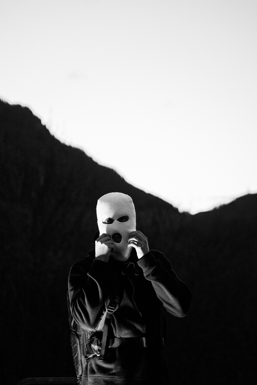 Free A person wearing a mask in a dramatic mountain backdrop, grayscale image. Stock Photo