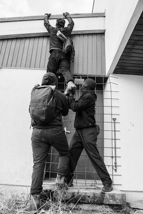Grayscale Photo of a Group of People Climbing a Building