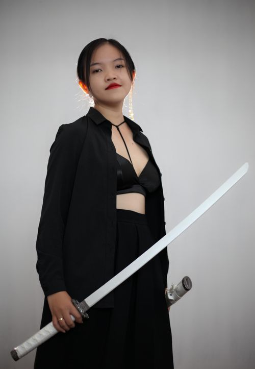 Free Content Japanese female with katana in hand wearing black outfit with bra looking at camera while standing on white background Stock Photo