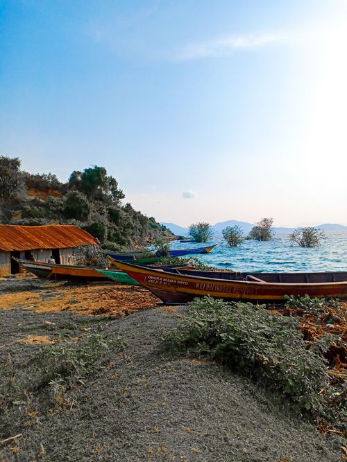 Free Vibrant boats docked on a scenic lakeside with lush greenery and distant hills. Stock Photo