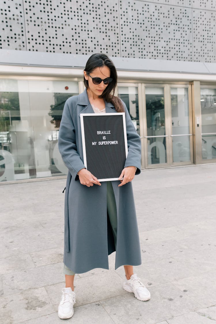 Woman Wearing Black Sunglasses Holding A Poster