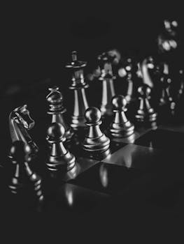 Black and white photo of chess pieces arranged on a chessboard, showcasing strategy and focus.