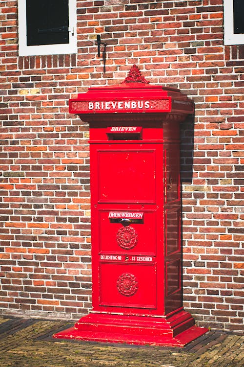 A Red Letterbox beside a Brick Wall