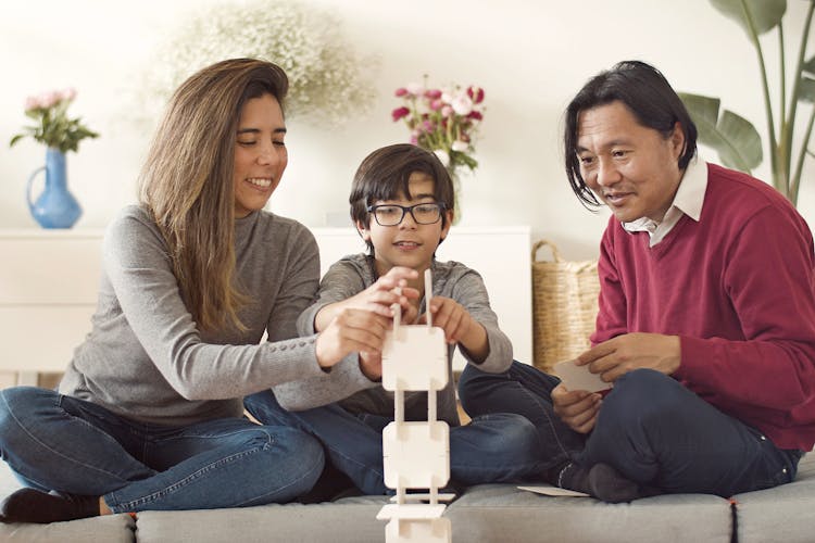 A Family Building A Tower With White Square Boards