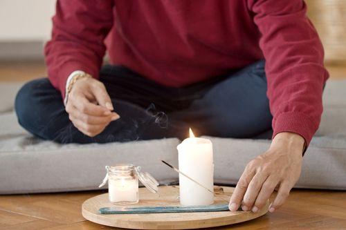 Free A man engages in aromatherapy and meditation using candles and incense for relaxation. Stock Photo