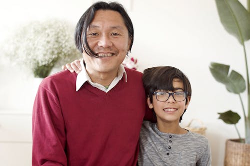 Free Man in Red Long Sleeve Shirt Standing Beside a Boy Stock Photo