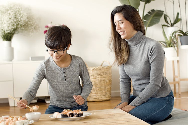 Mother And Child Eating Sushi At Home