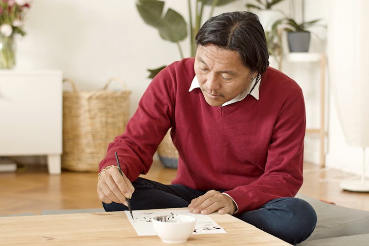 Man Sitting On Floor Drawing At Home