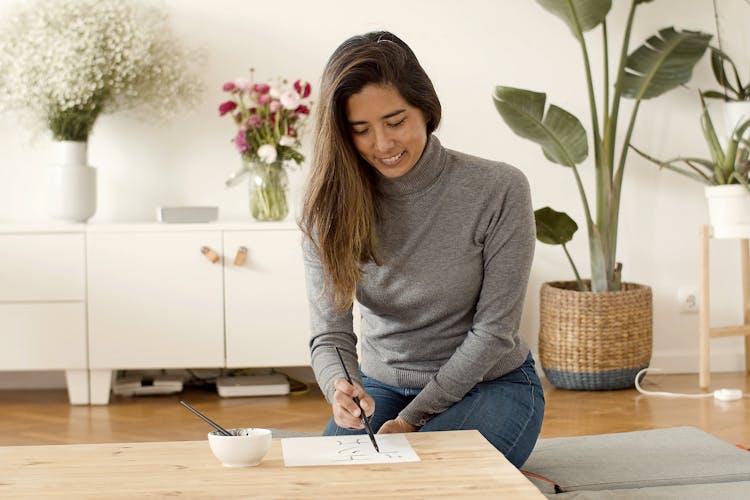 A Woman In Gray Turtleneck Sweater Drawing On White Paper On A Wooden Table