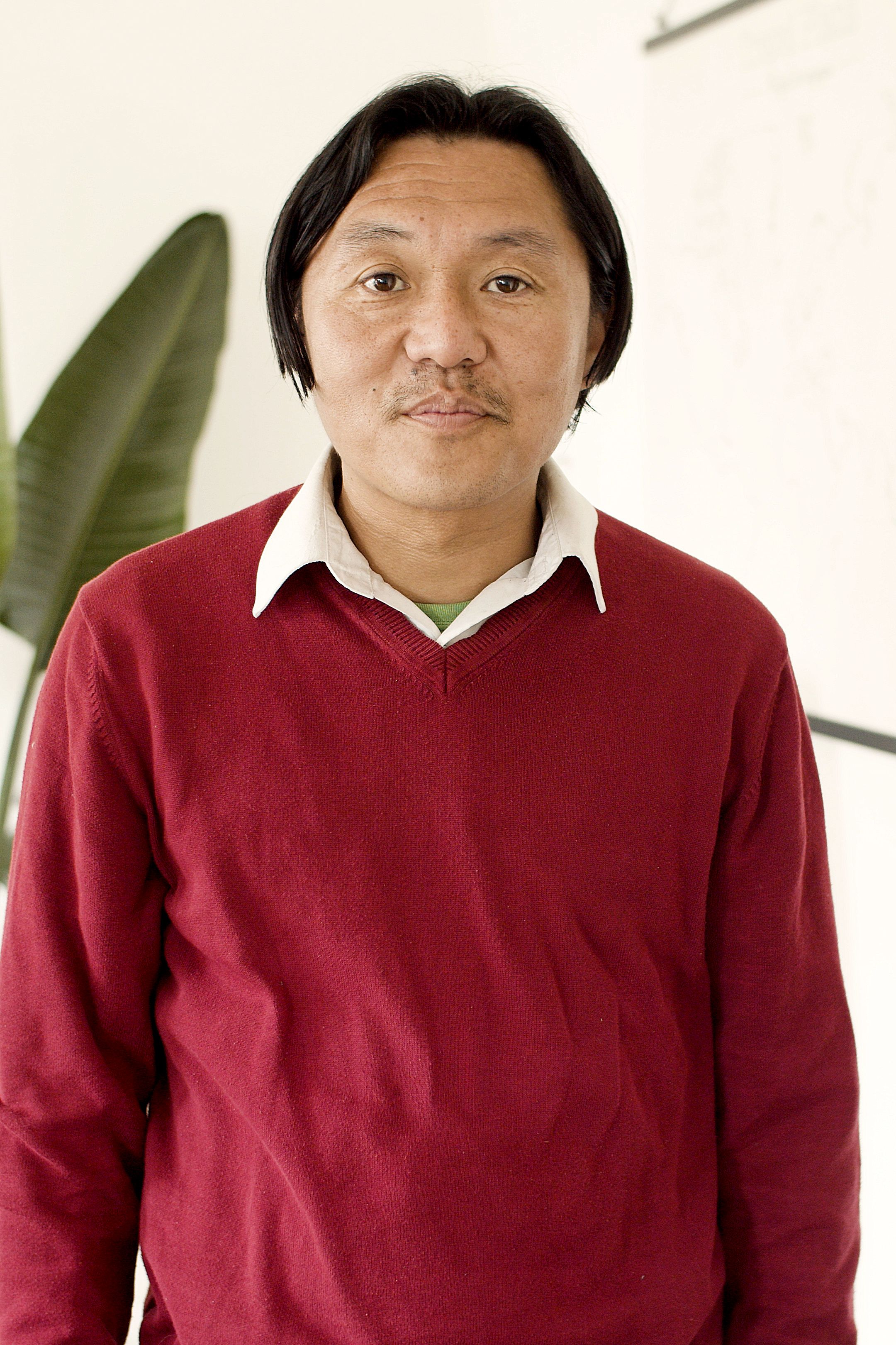Casual portrait of an adult man in a red sweater, taken indoors, with a relaxed expression.