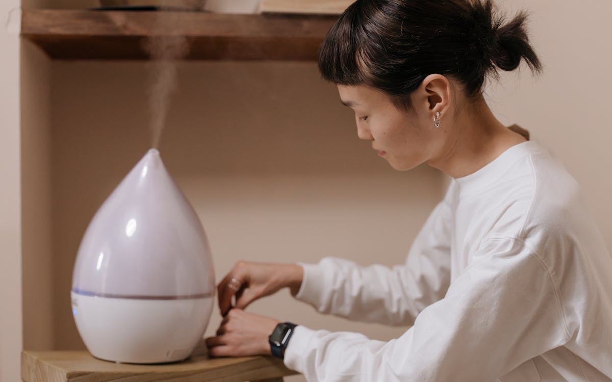 A woman adjusts a humidifier indoors, promoting relaxation and air quality.