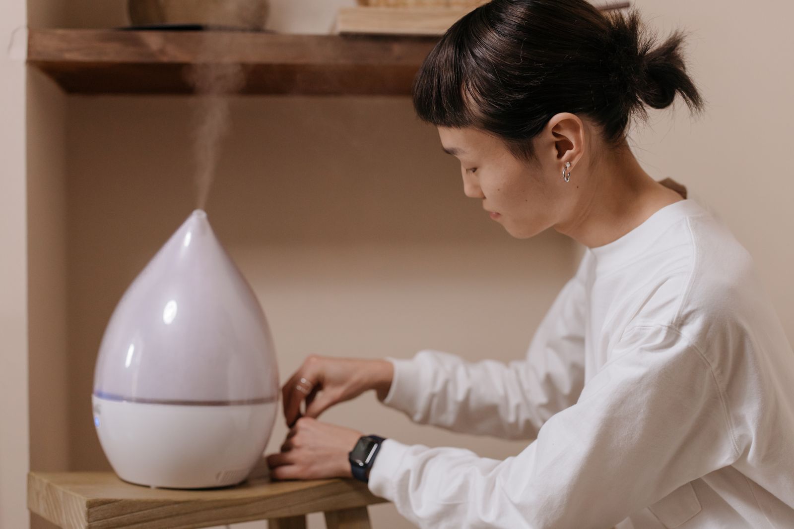 室内に置かれた加湿器の設定を手で操作している様子