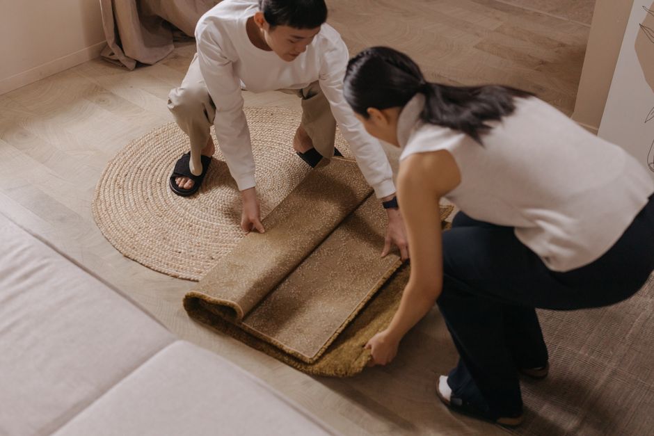 A couple rolls out a rug in a comfortable and stylish living room setting.