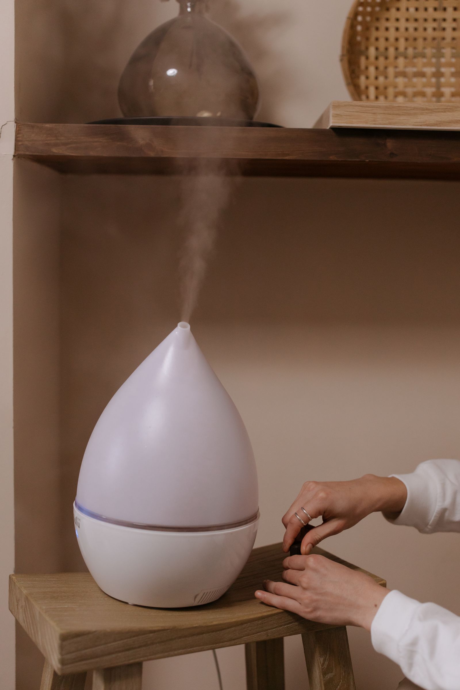 A modern humidifier releasing warm vapor on a wooden stool in a cozy room