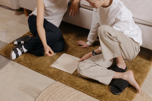 
A Couple Doing a Transparent Puzzle while Sitting on a Rug