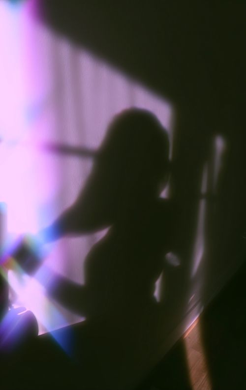 Free Mysterious silhouette of a woman with rainbow effect on the wall creating an artistic shadow. Stock Photo