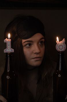 A woman wearing an eye mask celebrates her 18th birthday with lit candles in bottles.