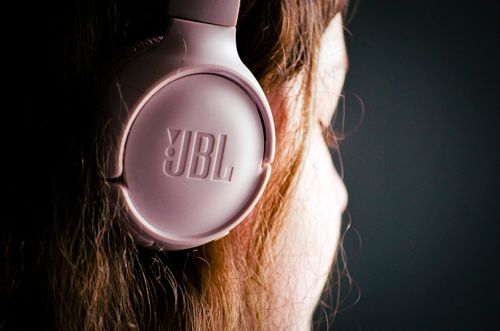 Free A close-up of a woman wearing pink JBL headphones, showcasing modern audio technology. Stock Photo