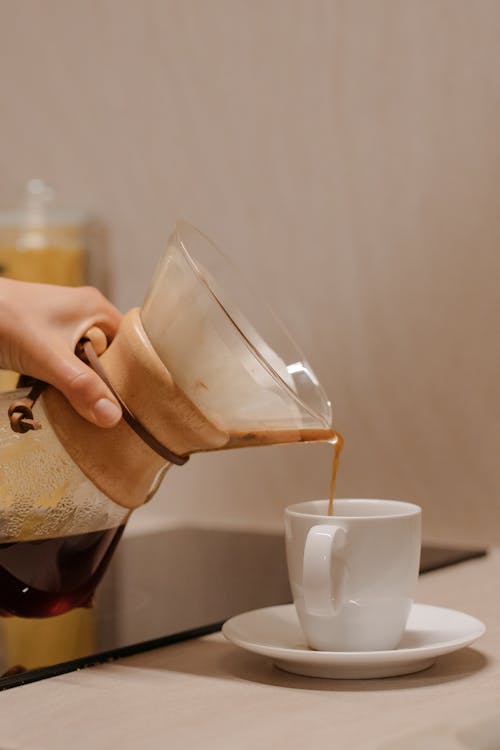 Close-up of a Person Pouring Coffee from a Coffee Pot into a Cup 