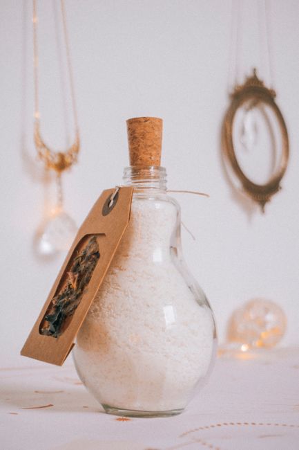 Fotomural Una botella de vidrio decorativa llena de sales de baño y adornada con una etiqueta rústica, perfecta para la estética del spa.